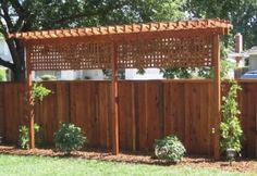 a wooden fence in the middle of a yard with potted plants and trees around it