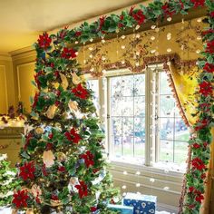 a decorated christmas tree sitting in front of a window next to a table with presents on it