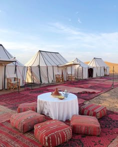 several tents set up in the desert with tables and stools on top of them