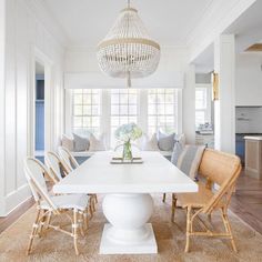 a dining room table with chairs and a chandelier hanging from it's ceiling