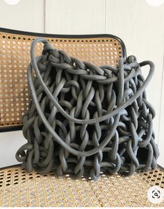 a gray purse sitting on top of a wicker chair