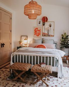 a white bed sitting in a bedroom next to a wooden table and two stools