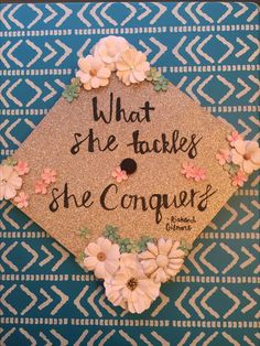 a graduation cap with flowers and the words what she takes she conquers on it