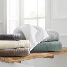 towels folded on top of a wooden shelf in front of a window