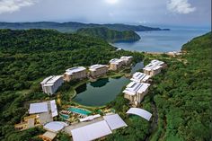 an aerial view of the resort surrounded by trees and mountains, with water in the foreground