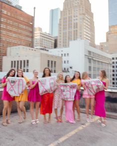 a group of young women holding up signs in the air with city buildings behind them