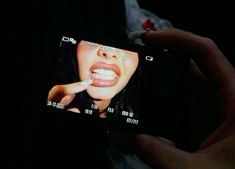 a person holding up a cell phone to take a photo with their teeth in the dark