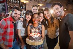 a group of people standing around a birthday cake