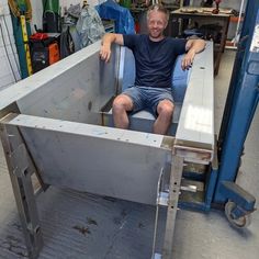 a man sitting in the back of a metal container on top of a blue dolly