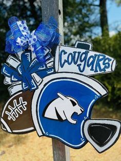 a wooden sign with some blue and white decorations on it's side, hanging from a pole