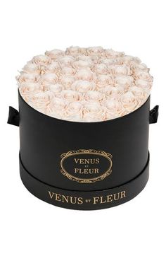 a round black box with white roses in the center and gold trimmings on top