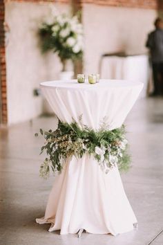 a white table topped with greenery and candles