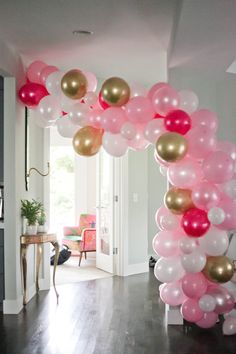 a balloon arch is decorated with pink, gold and white balloons