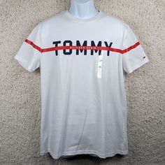 New With Tags! 100% Cotton. Bright White Pullover Tee-Shirt With Tommy Hilfiger Brand Logo, Navy Blue/Red. Review All Photos For Sizing And Condition. Close Up Photo Provided. Shoulder To Shoulder: 18" Armpit To Armpit: 20.5" Collar To Hem: 27" Sleeve Length: 8" White Tommy Hilfiger Tops For Streetwear, Tommy Hilfiger Cotton Crew Neck Shirt, Tommy Hilfiger White Crew Neck Shirt, White Casual Top With Three Stripes Branding, Casual White Top With Three Stripes Branding, Tommy Hilfiger White T-shirt With Graphic Print, White Cotton Tommy Hilfiger T-shirt, Tommy Hilfiger White Cotton Tops, Tommy Hilfiger White Cotton Shirt