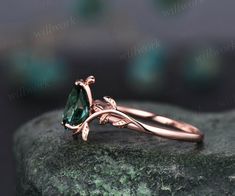 a rose shaped green diamond ring on top of a rock with leaves and vines around it