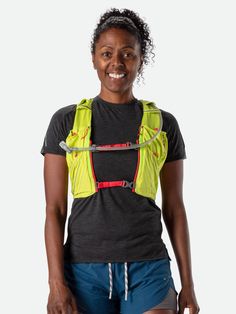 a woman wearing a safety vest and smiling at the camera with her hands in her pockets