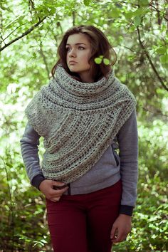 a woman standing in the woods wearing a knitted shawl and holding her hands on her hips