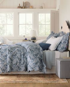 a bed sitting in a bedroom next to a window with lots of pillows on top of it