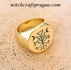 a gold ring with an image of the sun and moon in it on top of sand