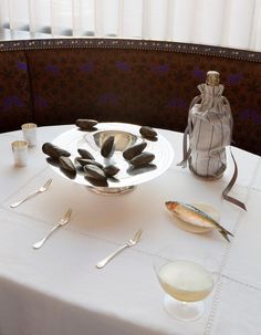 a table topped with a plate and silverware next to a wine glass on top of a white table cloth