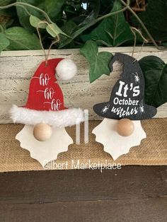 two christmas decorations are sitting next to each other on a table with greenery in the background