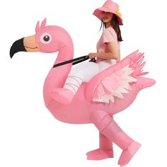 a woman riding on the back of a pink flamingo inflatable costume,