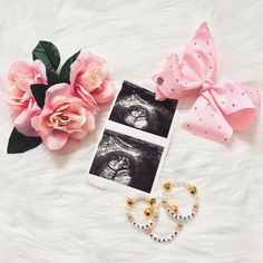 pink flowers and two pairs of earrings on a white fur surface with an image of a baby's eye