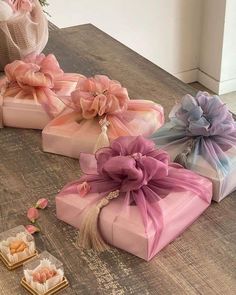 four wrapped gift boxes sitting on top of a wooden table