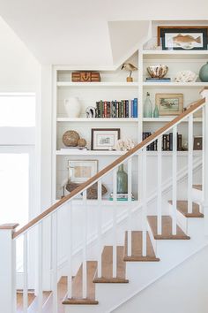 a white staircase with bookshelves and pictures on the wall