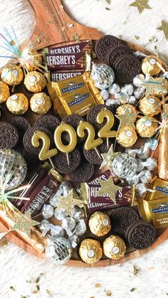 a wooden platter filled with lots of chocolates and cookies on top of a table