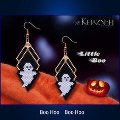 a pair of bead earrings with ghost and pumpkins in the background on display