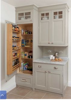 an open pantry in the corner of a room with white cabinets and drawers on both sides