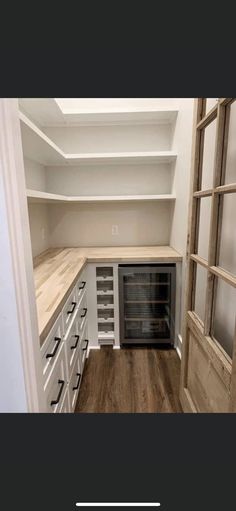 an empty kitchen with white cabinets and wood flooring