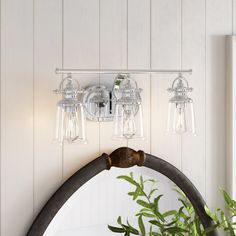 a bathroom vanity with three lights and a mirror on the wall next to a potted plant