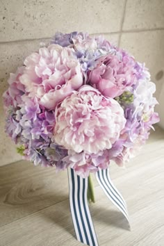 a bouquet of pink and purple flowers sitting on top of a wooden table next to a wall