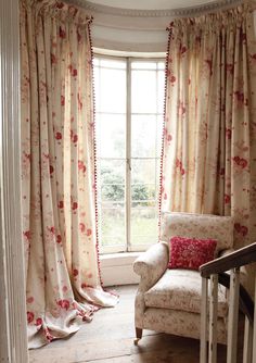 a chair sitting in front of a window next to a wooden bannister with flowers on it