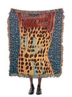 a woman is standing in front of an animal - print blanket with fringes on it