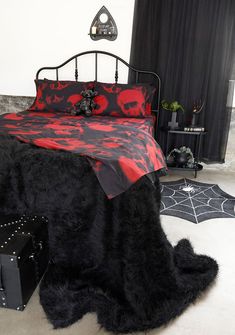 a bedroom with a bed covered in black and red sheets