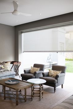 a living room filled with furniture and a large window covered in roller shades over the windows