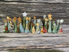 small ceramic christmas trees lined up against a wooden wall with stars on them and one standing out from the crowd