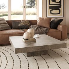 a living room with a couch, coffee table and rugs on the floor in front of large windows