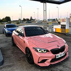 a pink car parked in front of a gas station with two other cars behind it