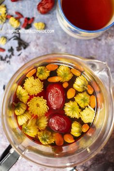 a cup filled with liquid and flowers next to a spoon