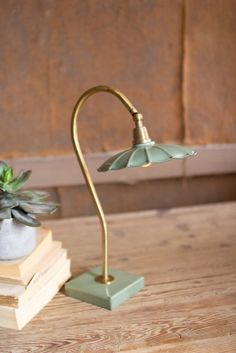 a green lamp sitting on top of a wooden table next to a stack of books