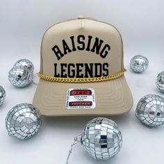 The Coco & Rho Original Raising Legends Trucker Hat is a staple for everyone. Adorned with a gold chain. The lettering is a soft velvet that gives it a raised and elevated look and feel. Made with a mesh back and adjustable strap for universal sizing! Introducing our exclusive Trucker Hat with a twist - each hat is a masterpiece, adorned with carefully curated patches for a unique touch. Crafted for the bold and the adventurous, this hat is more than an accessory; it's a statement of individuali Adjustable Gold Snapback Baseball Cap, Gold Adjustable Snapback Baseball Cap, Gold Snapback Hat With Curved Brim, Gold Adjustable Snapback Hat With Curved Brim, Gold Curved Brim Adjustable Snapback Hat, Adjustable Gold Snapback Hat, Adjustable Gold Snapback Cap, Gold Adjustable Snapback Hat, Adjustable Gold Trucker Hat