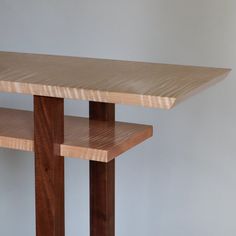 a wooden table with two shelves on each side and a white wall in the background