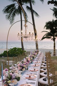 a long table is set up with plates and place settings for an elegant dinner on the beach