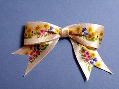 a close up of a bow with flowers on it's side, against a blue background