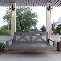 a wooden porch swing sitting on top of a white floor next to potted plants