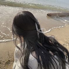 a woman with long hair standing on the beach